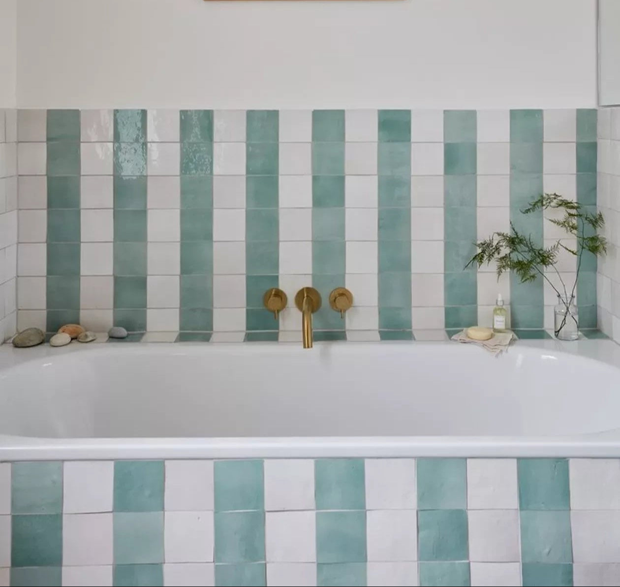 Handmade Moroccan Zellige tiles in alternating aqua green and white glaze installed in vertical stripe pattern around bathtub in 4x4 inches 2x2 inches 10x10 cm and 5x5 cm sizes