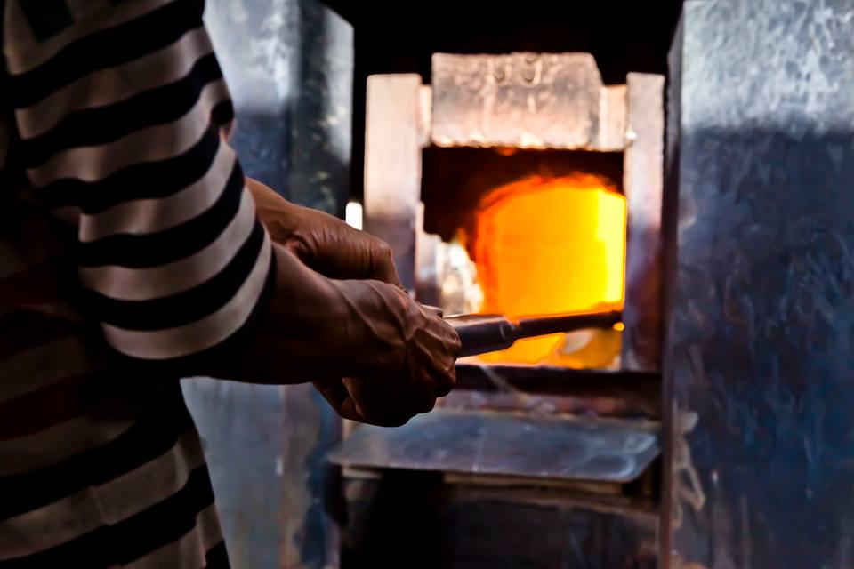 Artisan glassblower working with molten glass near a glowing furnace, House of Anouar