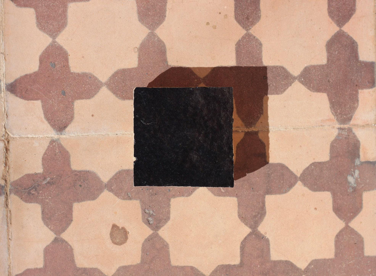Black zellige tile sample on a patterned floor, House of Anouar