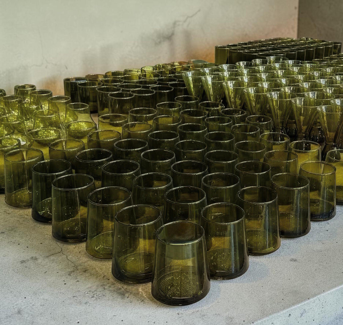 Bulk olive-green Beldi drinking glasses arranged in rows, House of Anouar