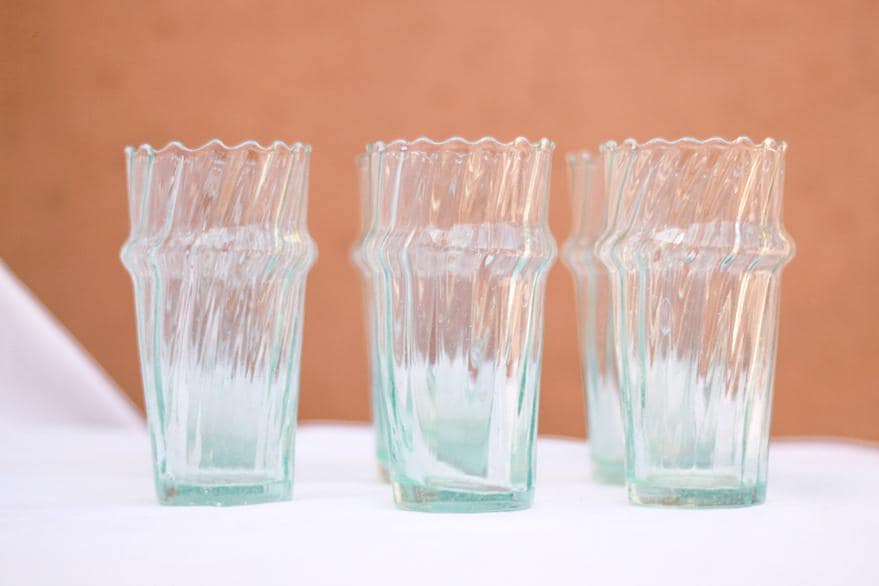 Clear fluted Beldi glasses against a terracotta background, House of Anouar