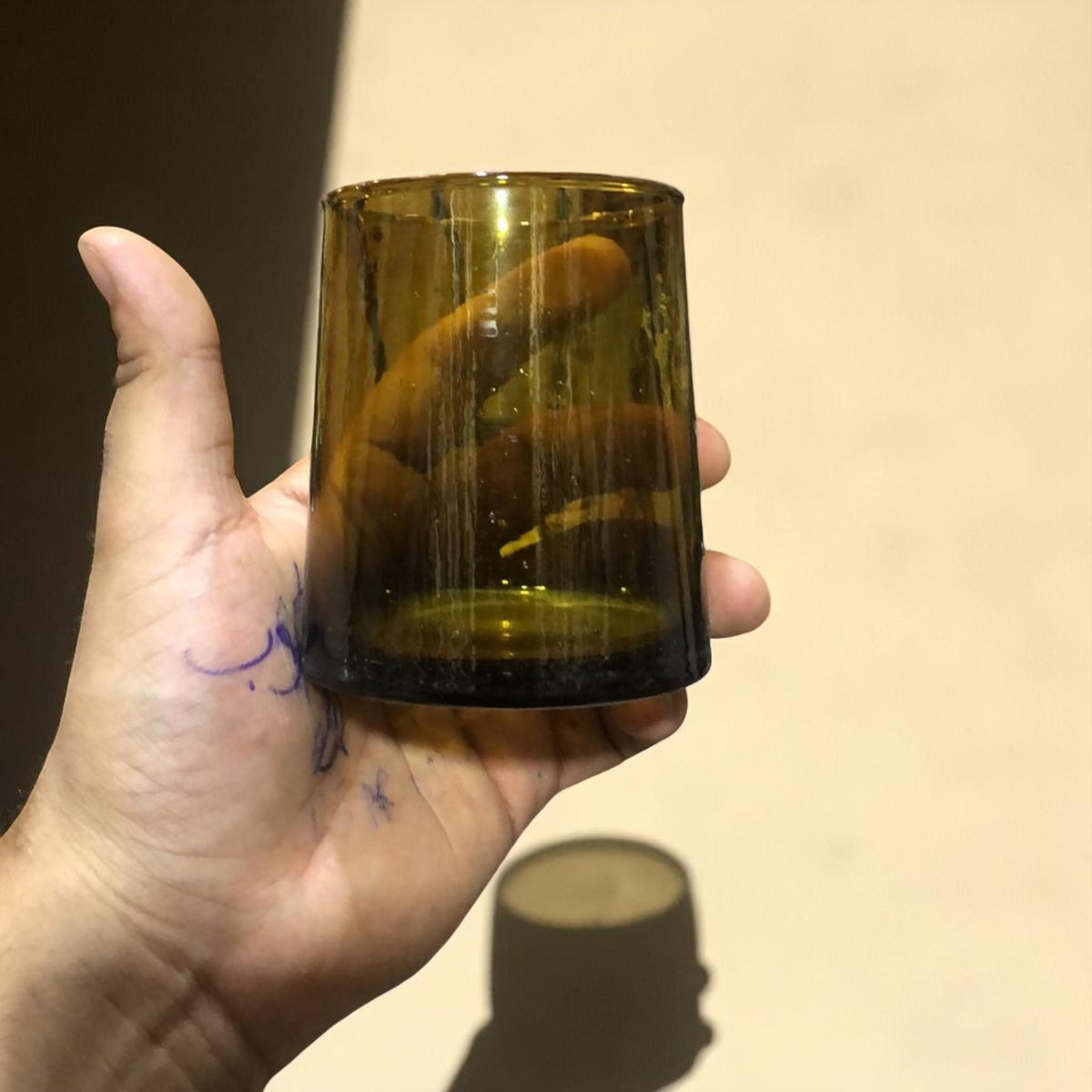 Hand holding a handcrafted olive green recycled Moroccan Beldi glass, House of Anouar