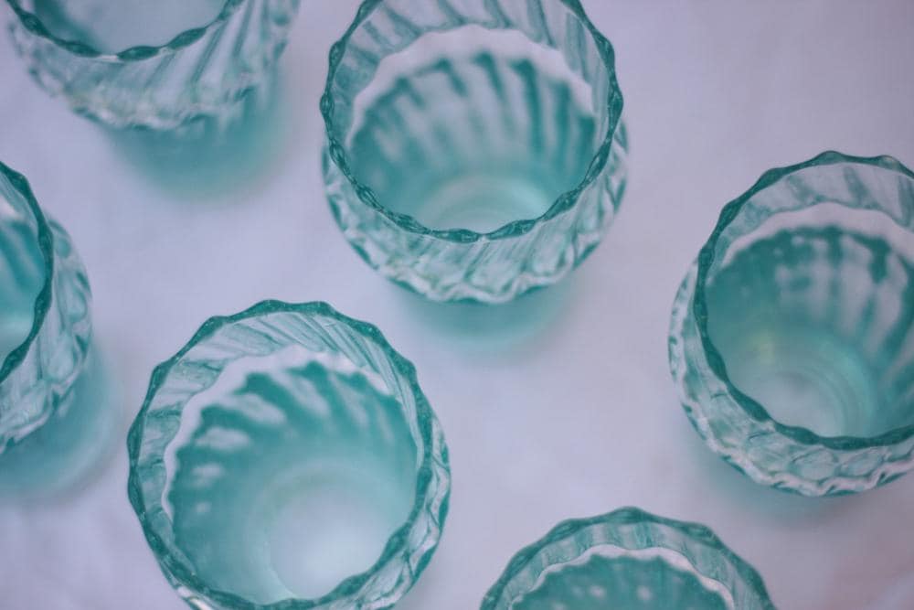 Handmade teal Moroccan glass cups with scalloped edges on a light surface, House of Anouar