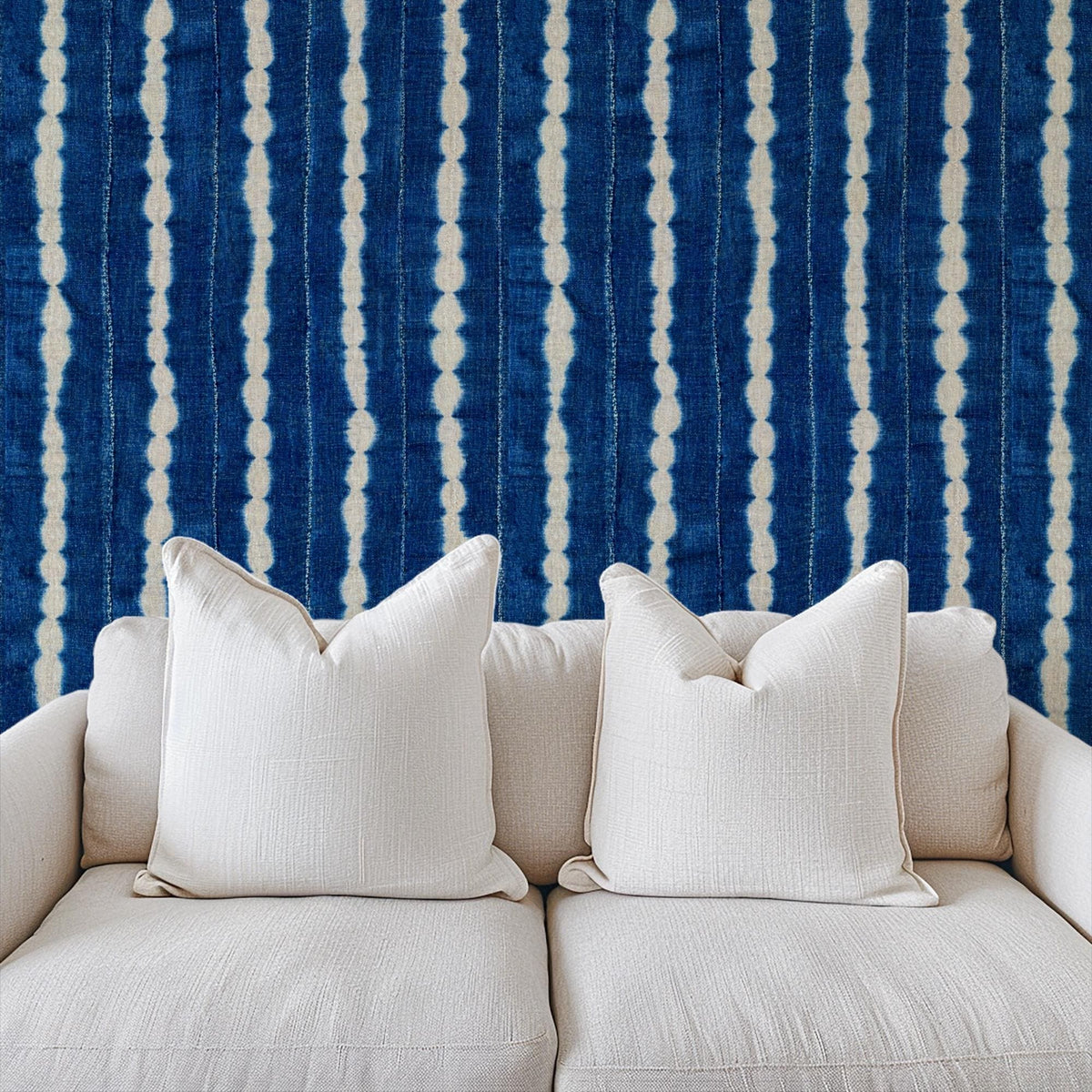 Indigo wavy-stripe wallpaper above a neutral sofa, House of Anouar