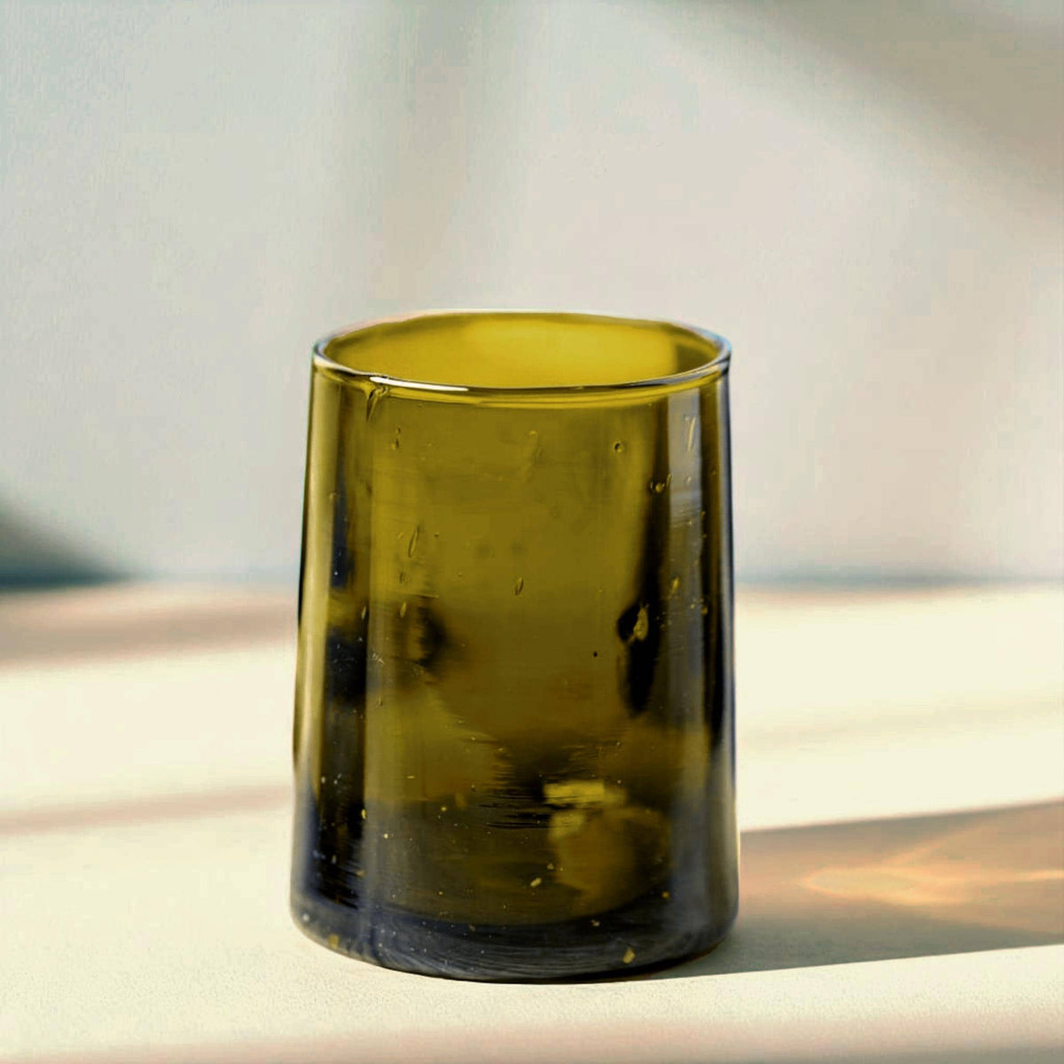 Short olive-green Beldi glass on a stone tabletop, House of Anouar