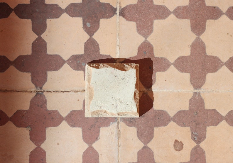 Single cream handmade Moroccan Zellige tile on burgundy red geometric patterned tiles, House of Anouar