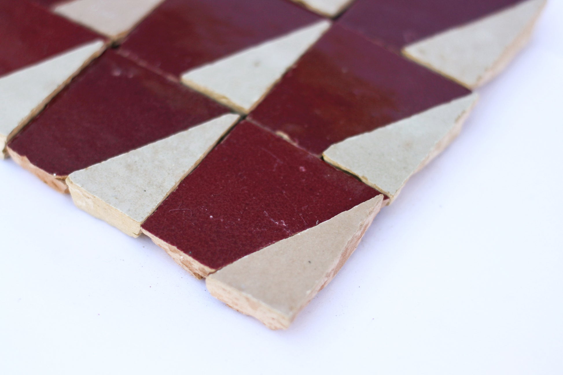 Handmade Moroccan Zellige tile in triangle geometric mosaic pattern in a deep burgundy red glaze and cream colored unique zellige tile